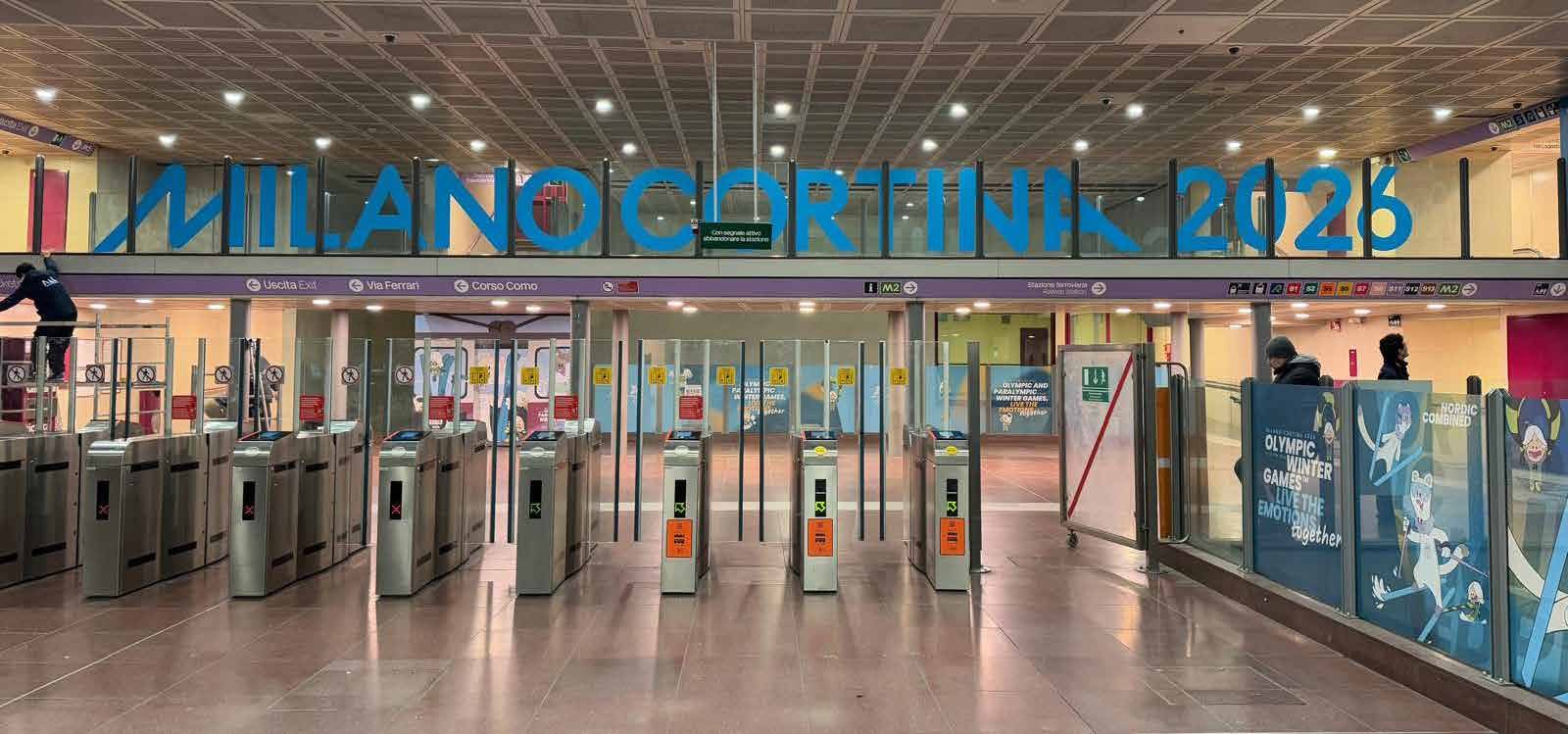 Tornelli della stazione M5 Garibaldi FS vestiti con la scritta MILANO CORTINA 2026 in blu olimpico
